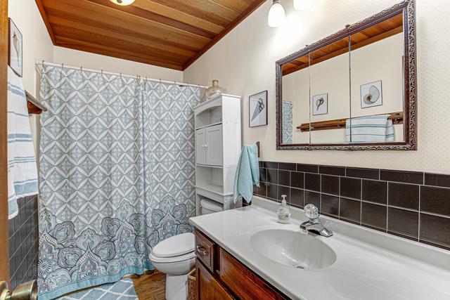 bathroom featuring toilet, a shower with curtain, wood ceiling, and vanity