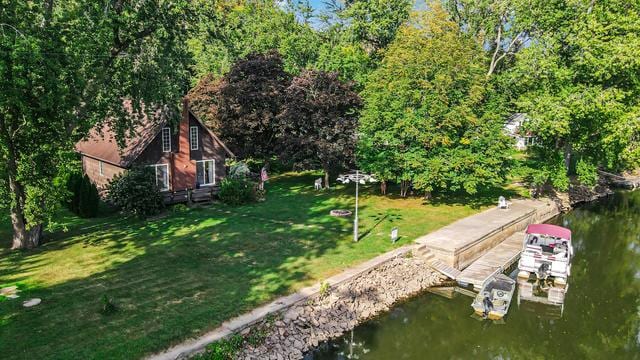 view of dock with a lawn and a water view