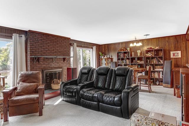 carpeted living room featuring wooden walls, a notable chandelier, and a brick fireplace