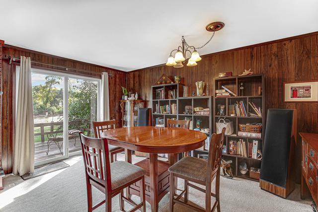 dining area with a notable chandelier, wood walls, and light colored carpet