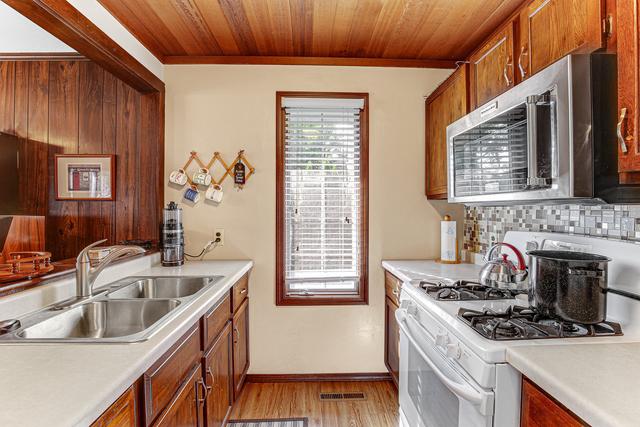 kitchen with a sink, light countertops, white gas stove, and stainless steel microwave