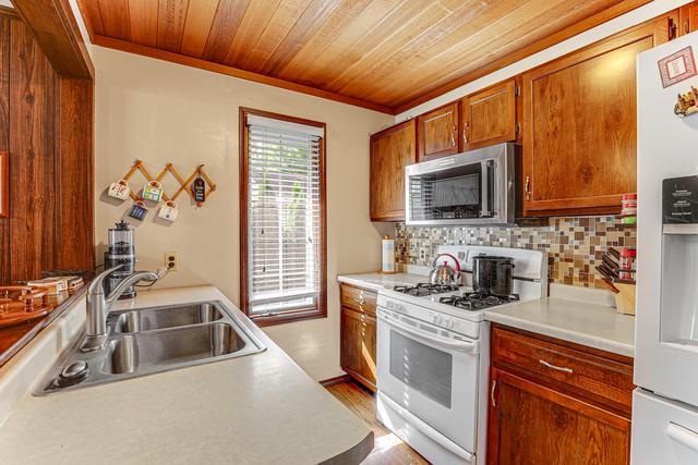 kitchen with crown molding, decorative backsplash, white appliances, light countertops, and a sink