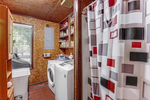 washroom with dark tile patterned floors, electric panel, laundry area, independent washer and dryer, and wallpapered walls