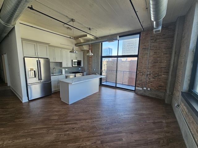 kitchen with a kitchen island, appliances with stainless steel finishes, a sink, and dark wood-type flooring
