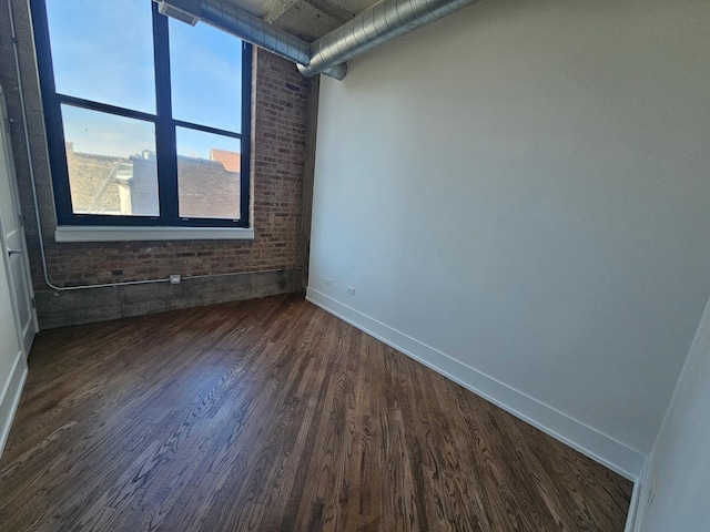 empty room with baseboards and dark wood-type flooring