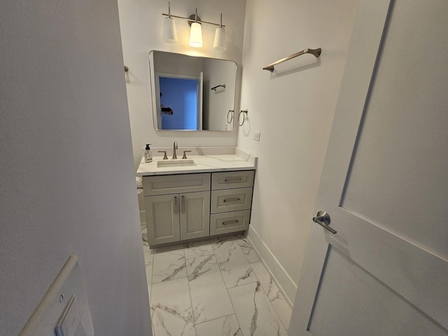bathroom with vanity, marble finish floor, and baseboards