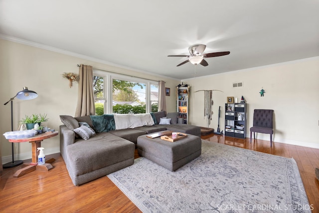 living room featuring baseboards, ornamental molding, ceiling fan, and wood finished floors