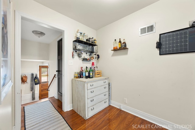 hall featuring baseboards, visible vents, and dark wood-style floors