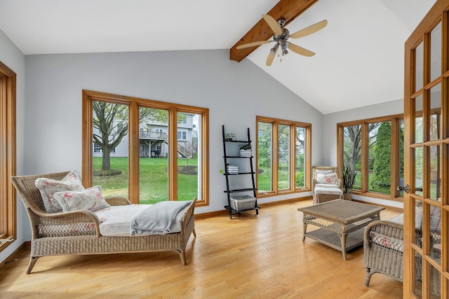 living area featuring ceiling fan, plenty of natural light, light wood-type flooring, high vaulted ceiling, and beamed ceiling