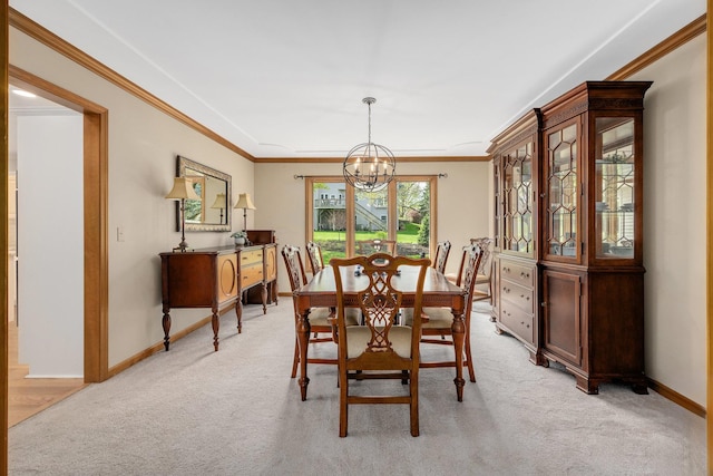 dining room with light colored carpet, a chandelier, ornamental molding, and baseboards
