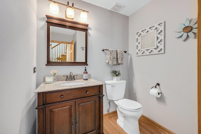 bathroom featuring wood finished floors, toilet, vanity, and baseboards