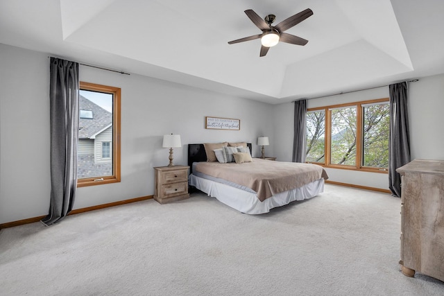 bedroom featuring a raised ceiling, baseboards, carpet flooring, and a ceiling fan