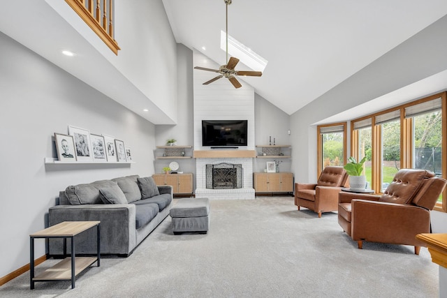 carpeted living area with high vaulted ceiling, ceiling fan, a fireplace, a skylight, and recessed lighting