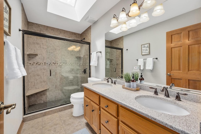 bathroom with a skylight, toilet, a shower stall, double vanity, and tile patterned flooring