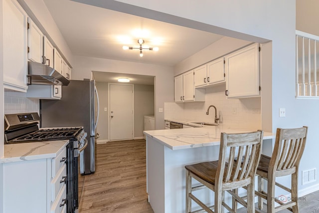 kitchen with visible vents, under cabinet range hood, white cabinets, a sink, and stainless steel appliances