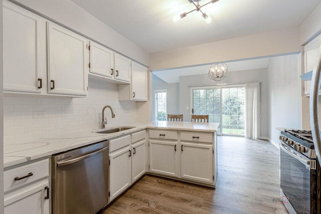 kitchen featuring a notable chandelier, a sink, stainless steel appliances, white cabinetry, and a peninsula