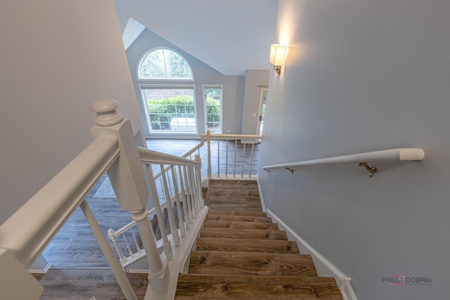 staircase featuring baseboards, lofted ceiling, and wood finished floors