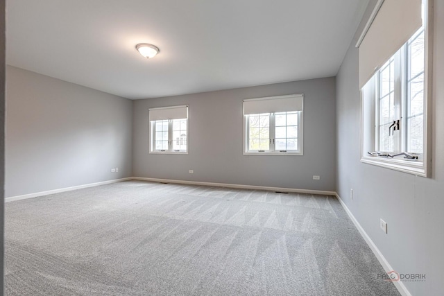 carpeted empty room featuring baseboards