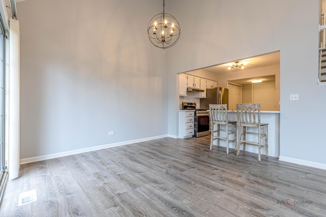 unfurnished living room featuring an inviting chandelier, baseboards, and wood finished floors