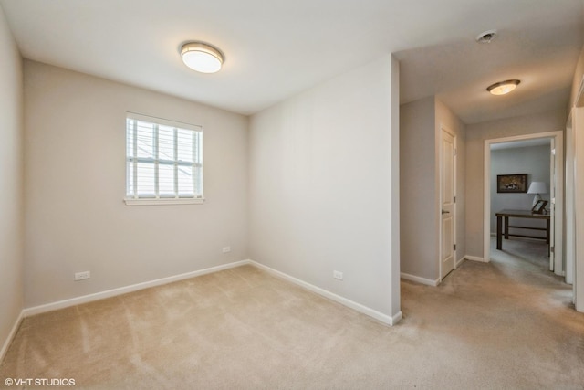 spare room featuring baseboards and light colored carpet