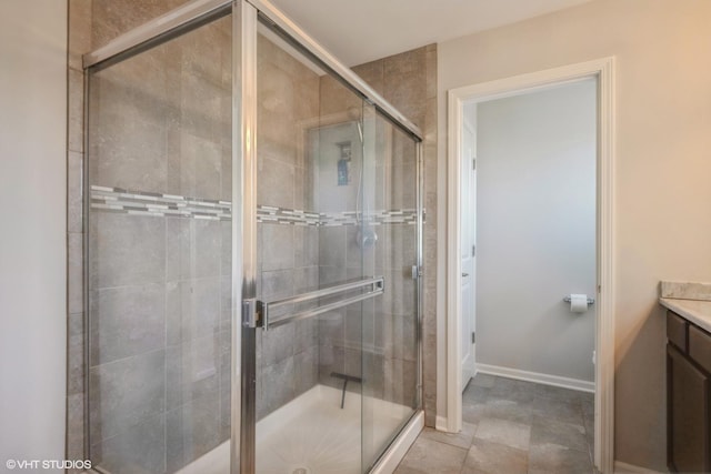 bathroom featuring vanity, baseboards, and a stall shower