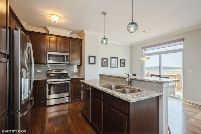 kitchen featuring dark wood-style flooring, appliances with stainless steel finishes, tasteful backsplash, a sink, and an island with sink