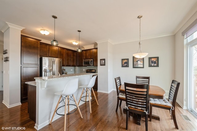 kitchen with backsplash, dark brown cabinets, appliances with stainless steel finishes, and dark wood-style floors