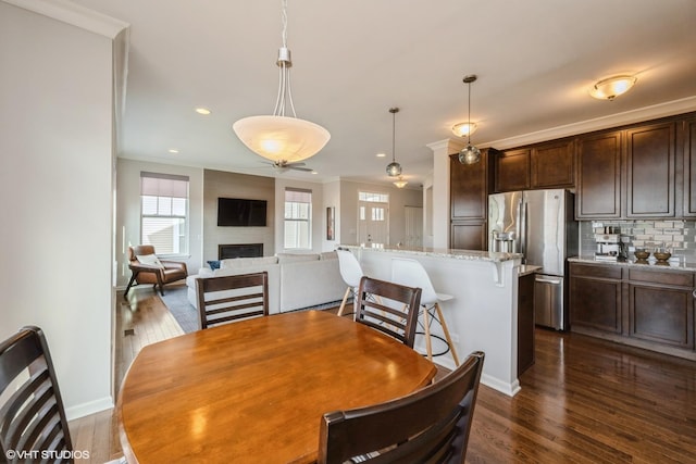 dining room featuring crown molding, dark wood-type flooring, and plenty of natural light