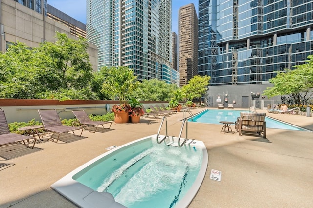 community pool with a patio, a view of city, and a hot tub