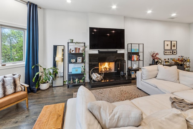 living area featuring recessed lighting, a warm lit fireplace, visible vents, and dark wood-style floors