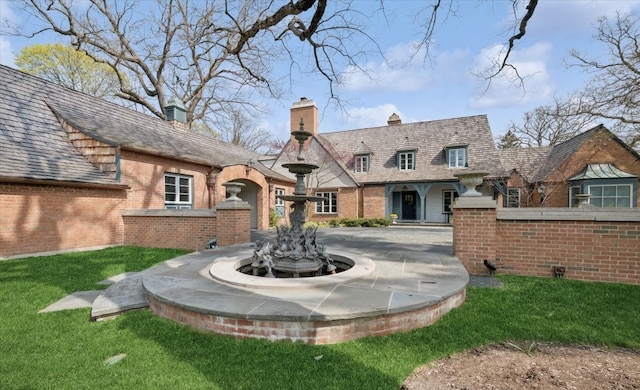 exterior space with brick siding, a lawn, and a chimney