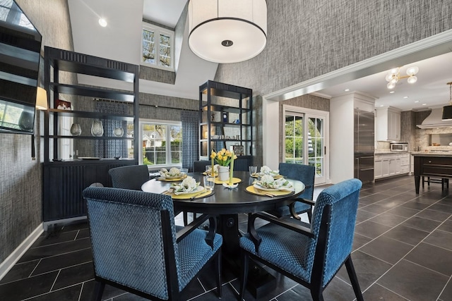 dining space with a towering ceiling, dark tile patterned flooring, and wallpapered walls