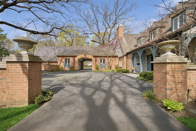 view of front of house with a chimney, driveway, and brick siding