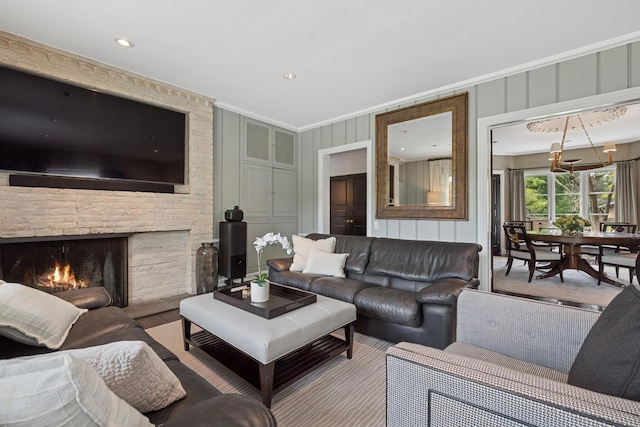 living room with a fireplace, recessed lighting, ornamental molding, and a decorative wall