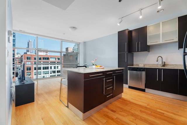 kitchen featuring dishwasher, a sink, light wood-type flooring, a center island, and modern cabinets