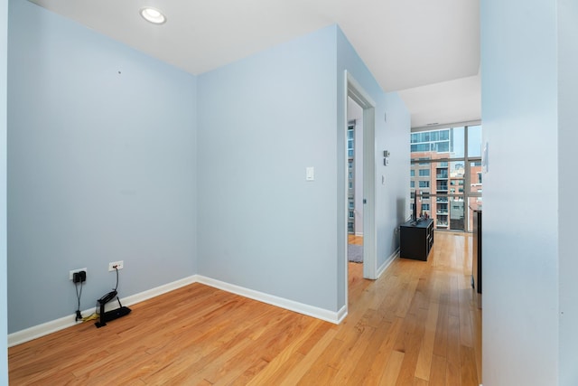 corridor featuring light wood-style floors, baseboards, and a wall of windows