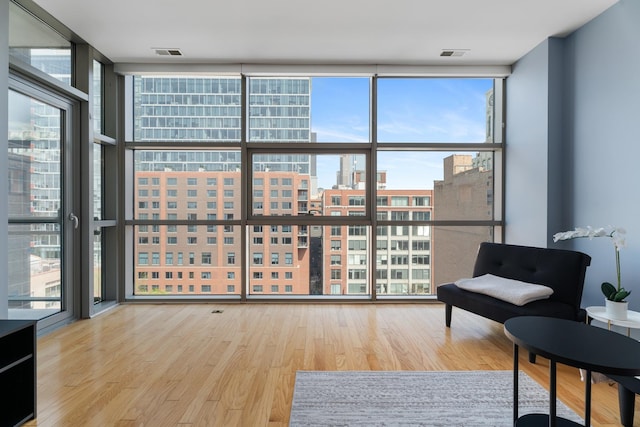 sitting room featuring expansive windows, healthy amount of natural light, wood finished floors, and a city view