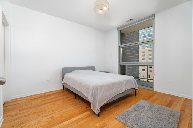 bedroom with wood finished floors, baseboards, and expansive windows