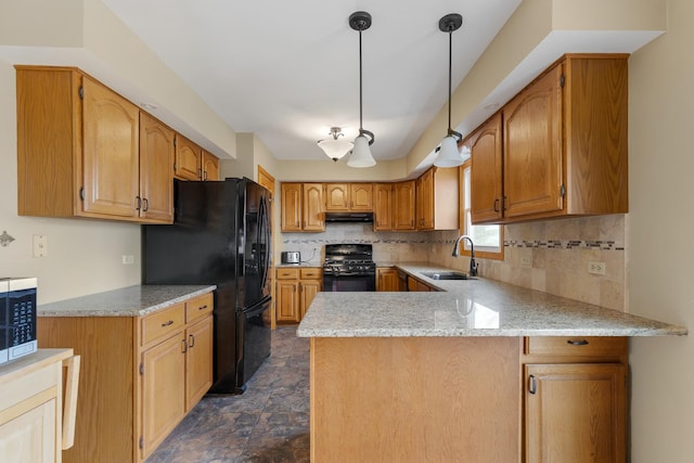 kitchen featuring a sink, a peninsula, decorative backsplash, under cabinet range hood, and black appliances