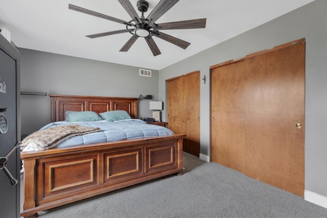 carpeted bedroom with visible vents, a ceiling fan, and multiple closets