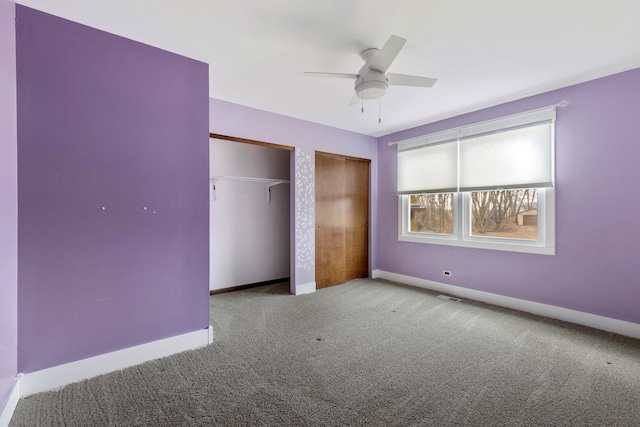 unfurnished bedroom featuring baseboards, ceiling fan, carpet flooring, and two closets