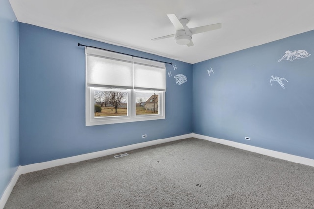 carpeted spare room featuring baseboards, a ceiling fan, and visible vents