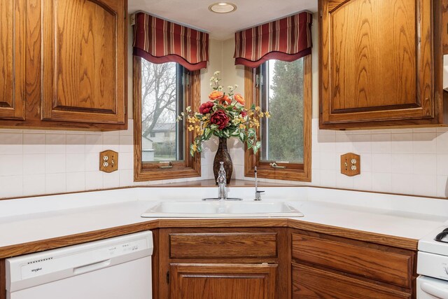 kitchen featuring white dishwasher, light countertops, brown cabinets, and a sink