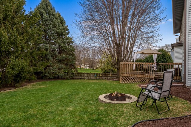 view of yard with fence, a wooden deck, and an outdoor fire pit