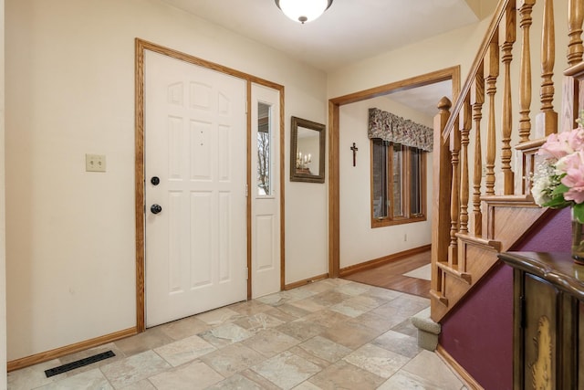 entryway with visible vents, stairs, baseboards, and stone finish floor