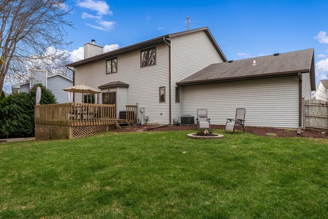 rear view of property featuring a lawn, a chimney, cooling unit, and a deck