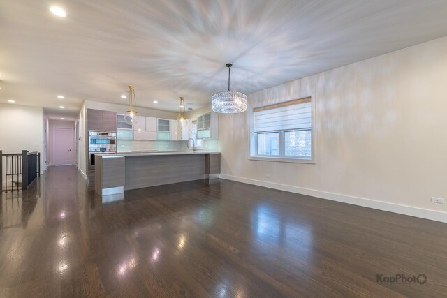 kitchen with an inviting chandelier, a peninsula, baseboards, modern cabinets, and a sink
