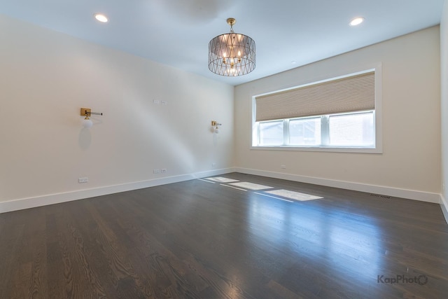 empty room featuring baseboards, dark wood finished floors, and a chandelier