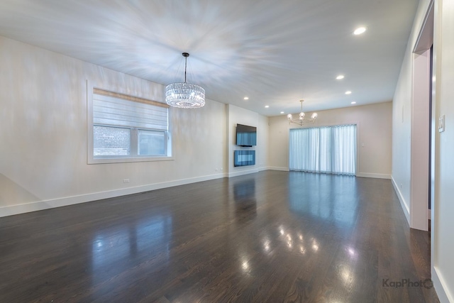 empty room with dark wood-style flooring, an inviting chandelier, recessed lighting, baseboards, and a wealth of natural light