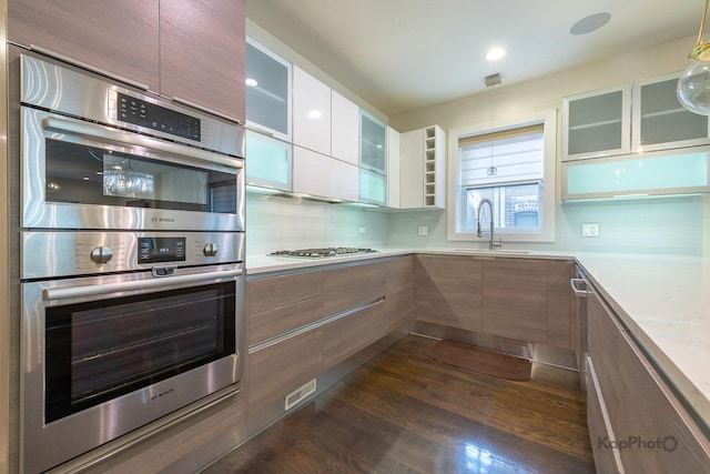 kitchen featuring a sink, light countertops, stainless steel appliances, tasteful backsplash, and modern cabinets